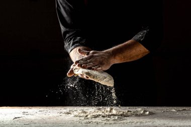 Erkek eli pizza için hamur yapıyor. Pizza hamuru. Ekmek pişiriyorum. Hamuru yoğurmak. Karanlık arka planda izole edilmiş. Metin için boşluk.