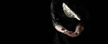 Hamurlu pizzacının eli, havaya uçuşan toz un. Şefin elleri un ile dondurucu bir hareketle koyu arkaplanda izole edilmiş un bulutu gibi havada süzülür..