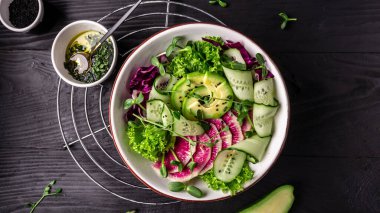 Vejetaryen Buda kasesi. avokado ve karpuz turp salatası marul yaprakları ve mikroyeşil lahana, salatalık ve sağlıklı besin karışımı. Üst Manzara. Düz yatıyordu.