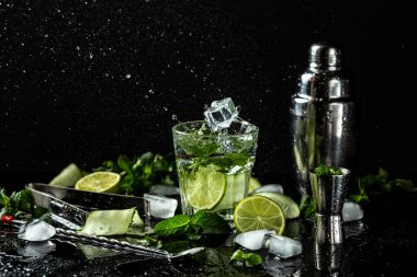 Taze mojito kokteyli, limonlu, naneli ve buzlu koyu arkaplanda kavanoz bardaklı. Dondurucu hareketle içmek, sıvı sıçraması. Yaz turunçgilleri, ferahlatıcı içecekler, kokteyller, limonata..