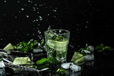 Salatalık suyu. Diyet sağlıklı beslenme ve kilo kaybı için nane yapraklı yaz serin suyu. Sıvı sıçramalı taze içecek, koyu arka plandaki kavanoz bardağında dondurucu hareket..