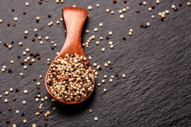 İşlenmemiş kinoa tohumunu taş bir arka planda ahşap kepçeyle karıştırdım. Süper gıda ürünü. Pankart, menü, tarif, mesaj için yer. en üstteki görünüm.