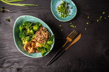 Siyah arka planda ıspanaklı, mantarlı brokoli ve kinoalı salata. Lezzetli kahvaltı ya da atıştırmalık. Üst görünüm.