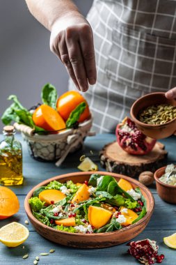 Ispanaklı hurma salatası, fındık, keçi peyniri, nar, kabak çekirdeği. Dondurucu yiyecekler ev mutfağında aşçıbaşı tarafından vejetaryen salatayla hazırlanıyor. Sağlıklı vejetaryen gıda konsepti.