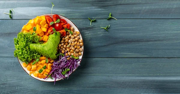 Buddha bowl vegetarian, vegan dish with avocado, tomato, red cabbage, chickpea, fresh lettuce salad, pumpkin, persimmon. banner, catering menu recipe place for text, top view.