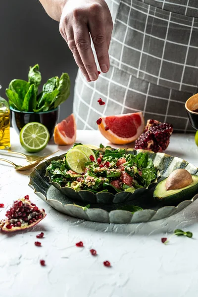Winter Salad with quinoa, spinach, avocado, grapefruit, pomegranate, nuts and microgreens, Freezer food prepare in process vegan salad by chef hand in home kitchen.