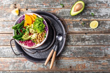 Buda kasesi vejetaryen, kızarmış nohut, avokado, hurma, ıspanak, avokado, karpuz turpu ve tohumlu vegan yemeği. Üst görünüm, düz görünüm, kopyalama alanı.