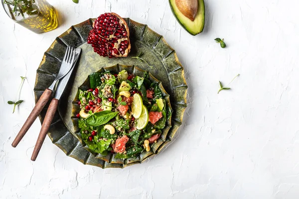 Trendy vegetarian, vegan winter salad with quinoa, spinach, avocado, grapefruit, pomegranate, nuts and microgreens. Healthy balanced eating Top view.