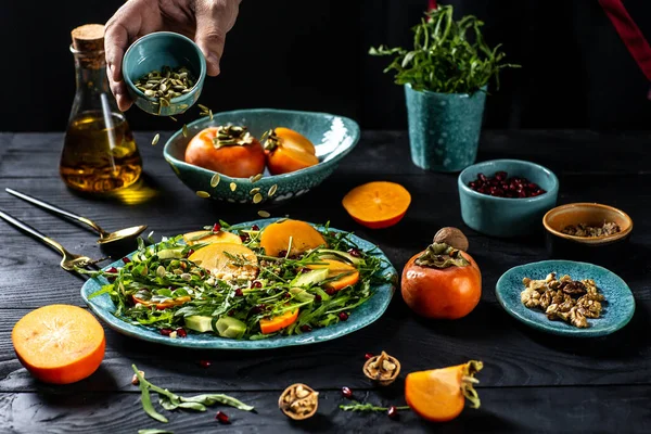 デジタルタブレットでレシピを次の男とアルグラと新鮮なおいしい柿のサラダを調理 アボカド カボチャの種 クルミ ザクロ 過程で冷凍食品の準備 — ストック写真