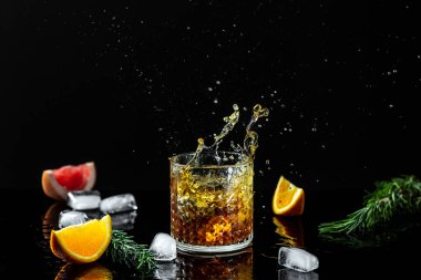 Siyah arka planda bir bardak viski. Alkol kokteyli. Düşen buz parçaları farklı yönlere uçar. Dondurma hareketi.
