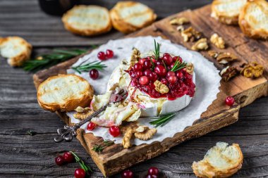 Taze biberiye, kızılcık sosu ve ahşap masada baget ekmeği ile fırında pişmiş camembert peyniri. Pankart, yemek servisi menü tarifi yeri, metin, üst görünüm.