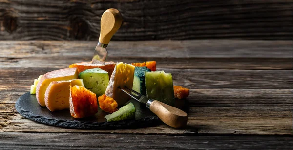 Ahşap arka planda farklı peynir çeşitleri. Peynir arka planı. Uzun afiş biçimi. Metin için boşluk.