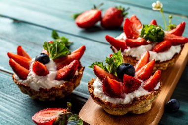 Kremalı, çilekli ve böğürtlenli meyveli turtalar ve tidewater yeşili arka plan. Yemek tarifi geçmişi. Kapat.