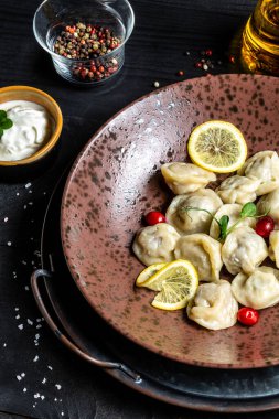 Beef and Pork Pelmeni - Rus Etli Hamur köfteleri siyah woden arka planda. Pelmeni, ravioli, etli börek. dikey resim,