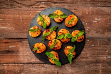 Yaz tatlısı. Olgun ızgara şeftali, bal ve nane yaprağı, yemek servisi, yemek tarifi geçmişi. Kapat.