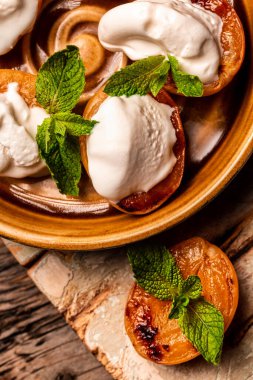 Krem şanti ve nane yapraklarıyla servis edilen enfes ızgara şeftaliler. Izgara şeftali, kayısı, nektarin ve dondurma..