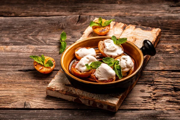 Delicious grilled peaches served with whipped cream and mint leaves. Grilled peaches, apricots, nectarines and ice cream.