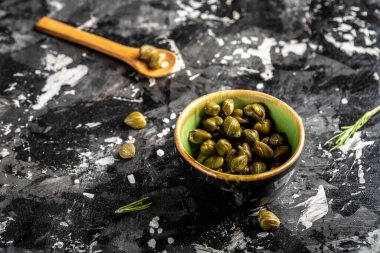 Seramik kasede marine edilmiş kapari. Capparis spinosa 'nın yenilebilir çiçek tomurcukları, gebre çalıları veya Çakmaktaşlar koyu bir arka planda yükseldi..