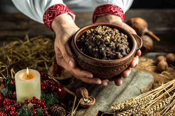 Kutya is a ceremonial grain dish. man in slavic shirt holding bowl with traditional kutia. Christmas sweet dishes in Ukraine, Belarus and Poland. Christmas dinner kutia.