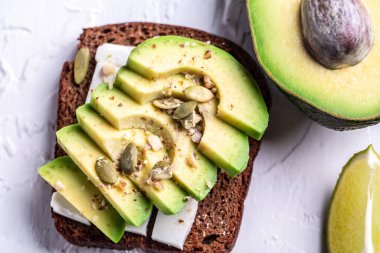 Avokado ve peynirli Çevre ürünleri kavramı. Organik tarım ürünleri, peynirler, mısır gevrekleri. Parmesan, feta, keçi peyniri. Arkaplan resmi. Boşluğu kopyala.