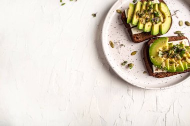 Avokado ve peynirli Çevre ürünleri kavramı. Organik tarım ürünleri, peynirler, mısır gevrekleri. Parmesan, feta, arka planda keçi peyniri. Düz yatıyordu.