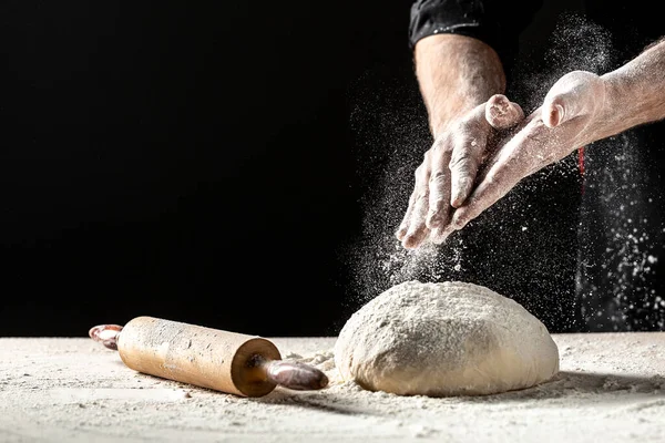 Photo of flour and men hands with flour splash. Cooking bread. Kneading the Dough. Isolated on dark background. Empty space for text.