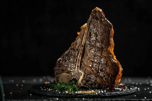 Aged Barbecue Porterhouse Steak. Beef T-Bone juicy steak rare beef with spices on a black table, banner, catering menu recipe place for text.