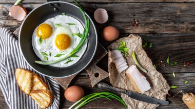 Ahşap masada lezzetli kızarmış yumurta ve domuz pastırması. Ukrayna mutfağı ya da Beyaz Rusya mutfağı. Pankart, yemek servisi menü tarifi yeri, metin, üst görünüm.