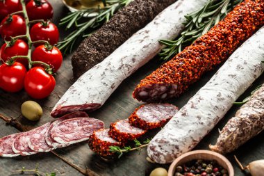 Kurumuş sucuk, fuet ve ahşap arka planda otlarla dilimlenmiş diğer sosisler. Geleneksel İspanyol sosisi. afiş, menü tarifi, üst görünüm.