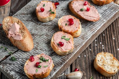 Kızarmış ekmeğin üzerine et ciğeri ezmesi, meyve tohumları ve ahşap kesme tahtasındaki baharat bitkisi. Üst görünüm