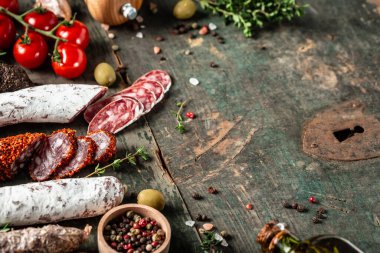 Kurumuş sucuk, fuet ve ahşap arka planda otlarla dilimlenmiş diğer sosisler. afiş, metin için menü tarifi yeri, üst görünüm.