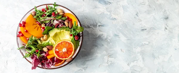 Salada de buda vegetariana saudável com abacate, caqui, laranja sangue, nozes, espinafre, rúcula e romã em um fundo claro, Formato de bandeira longa, vista superior — Fotografia de Stock