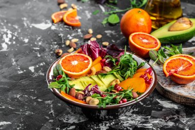 İçinde avokado, hurma, kan portakalı, fındık, ıspanak, roka ve nar bulunan Buda kasesi. Sağlıklı dengeli beslenme. Üst görünüm