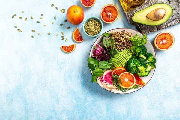 Healthy vegetarian dish with vegetables, avocado, blood orange, broccoli, watermelon radish, spinach, quinoa, pumpkin seeds. Buddha bowl. Balanced food. Delicious detox diet. Top view