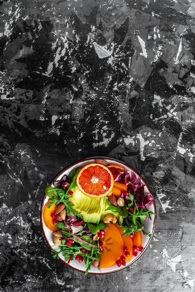 Buda prato tigela com abacate, cáqui, laranja sangue, nozes, espinafre, arugula e romã. Alimentação saudável e equilibrada. Vista superior. imagem vertical — Fotografia de Stock