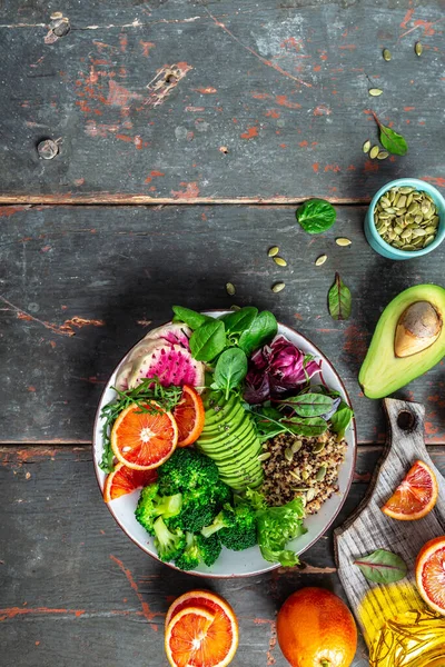 Healthy vegan lunch Buddha bowl salad with vegetables and fruit avocado, blood orange, broccoli, watermelon radish, spinach, quinoa, pumpkin seeds, Vegan, detox green Buddha bowl recipe.