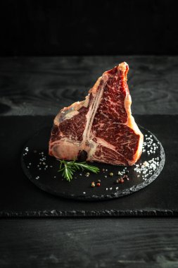 Biftek ve baharatlı baharat. Siyah arka plan. Amerikan et lokantasında ızgarada pişmiş gurme biftek..
