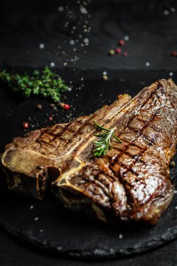 Yıllanmış ızgara Biftek Biftek. Biftek sulu biftek, az pişmiş biftek, siyah bir masada baharatlar, afiş, yemek tarifi..