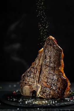 Yıllanmış ızgara Biftek Biftek. Biftek sulu biftek. Aşçı kızartma için baharat serpiyor. Klasik Amerikan yemeği. Et satışı, kasap dükkanı. dikey resim, metin için yer.
