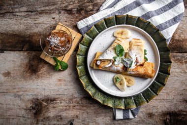 Çikolatalı krep ve muzlu beyaz tabak. İnce krep, blini. Lezzetli bir kahvaltı ya da arka planda atıştırmalık bir şeyler..