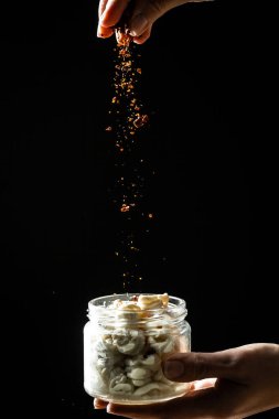 Cheesemaker peynirin nasıl yapıldığını gösteriyor, Şef elleri kavanoza baharat katıyor ve beyaz ahşap masada yağda marine ediliyor. Ekoloji ve eko-ürünler.