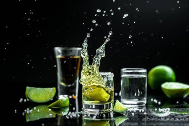 Siyah arka planda limonlu ve tuzlu Meksika tekilası. Metin için boşluk. konsept lüks içecek. Alkolik içki konsepti. Dondurucu hareketler, sıvı damlaları Meksika ulusal içeceği.