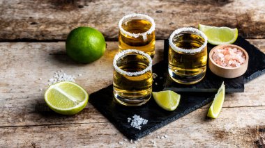 Kaba ahşap arka planda limonlu ve tuzlu Meksika Altın Tekilası. Alkolik içki konsepti. Meksika ulusal içeceği Uzun pankart biçimi.