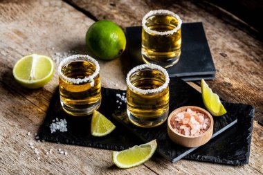 Üç tekila bardağı, tuzlu ve limonlu Meksika milli içeceği. Altın tekila shot 'ları. Meksika ulusal içeceği.