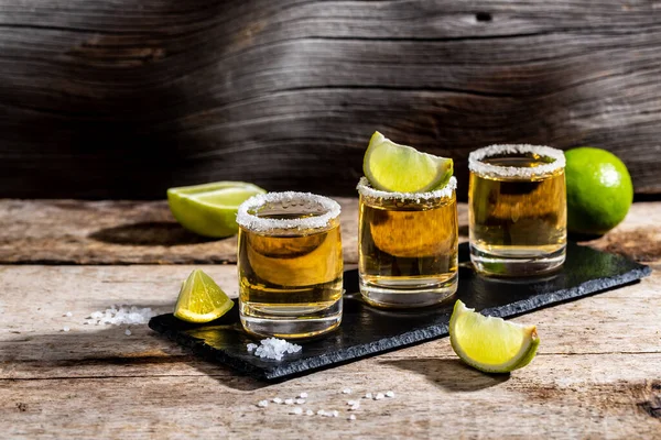 Mexican Gold Tequila with lime and salt on rustic wooden background. Alcoholic drink concept. Mexican national drink copyspace.