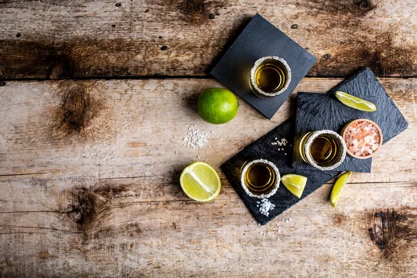 Mexican Gold Tequila with lime and salt on rustic wooden background. Alcoholic drink concept. Mexican national drink copyspace.