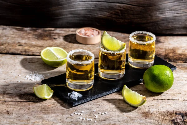 Three tequila shot glasses with salt and lime Mexican national drink. Golden tequila shots. space for text.