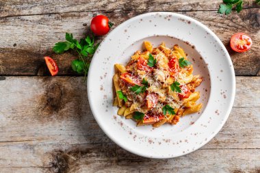 Domates soslu makarna et, parmesan peynirle süslenmiş domates ve ahşap masa. İtalyan yemeği. Üst görünüm.