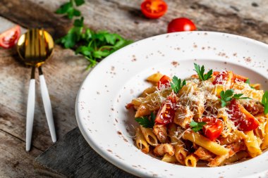 Baharatlı domates soslu tavuklu makarna, parmesan peyniri ve sade ahşap masa. Yemek tarifi geçmişi. Kapat..