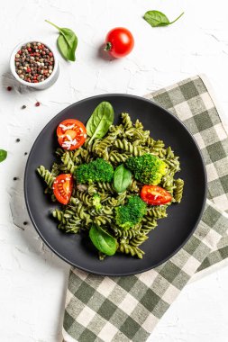 Makarna pesto vejetaryen kasesi. Çeri domatesli ıspanaklı yeşil makarna. dikey resim, metin için yer. en üstteki görünüm.